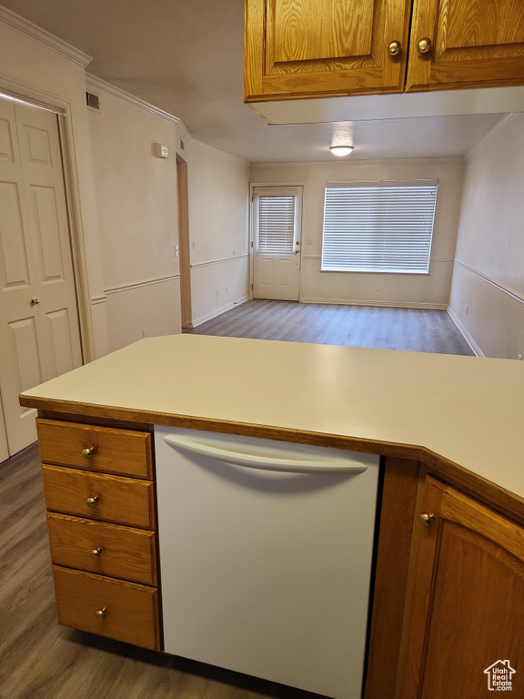 Kitchen with brown cabinets, light countertops, dishwasher, wood finished floors, and crown molding