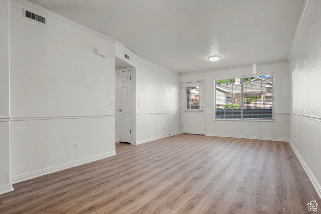 Spare room with ornamental molding and light wood finished floors