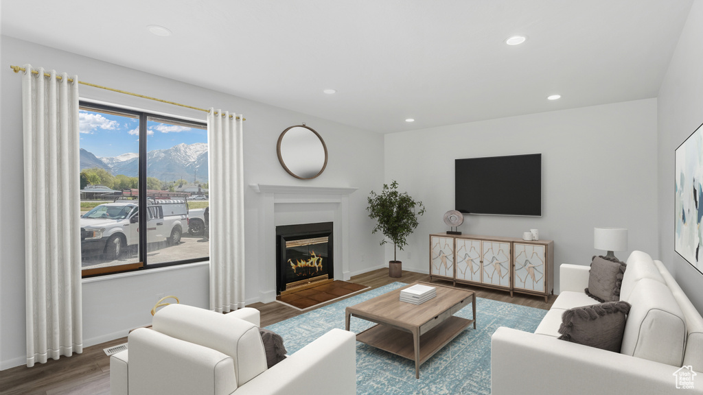 Living area featuring wood finished floors, a mountain view, recessed lighting, a fireplace with flush hearth, and baseboards