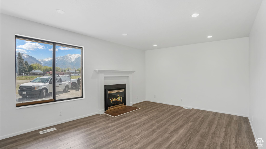 Unfurnished living room featuring visible vents, a glass covered fireplace, recessed lighting, a mountain view, and wood finished floors
