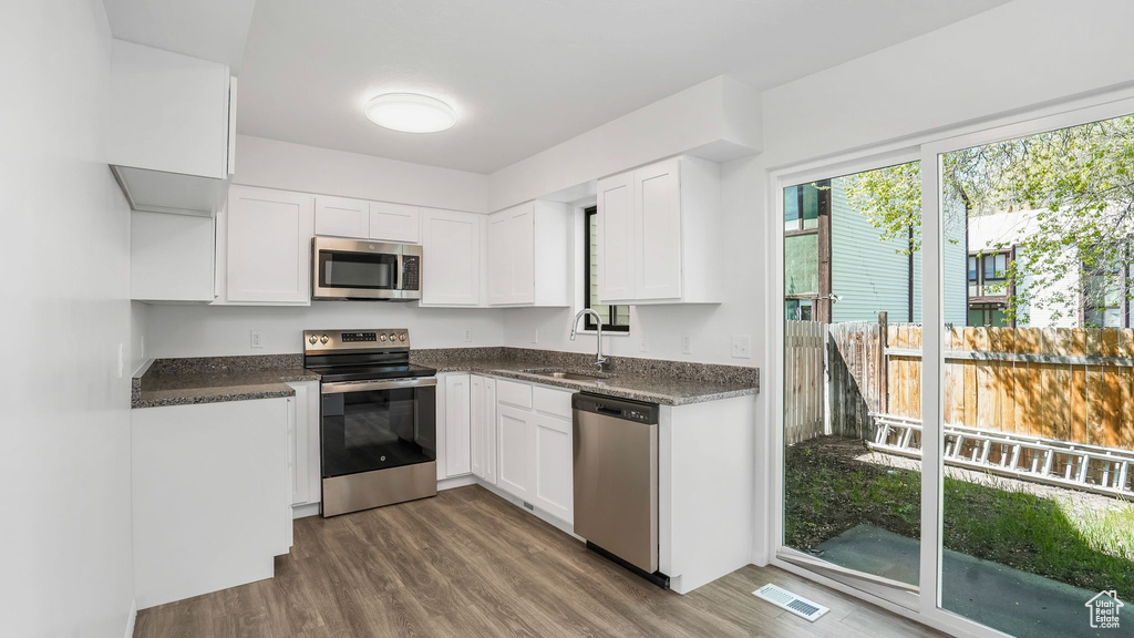 Kitchen with visible vents, stainless steel appliances, wood finished floors, and a sink