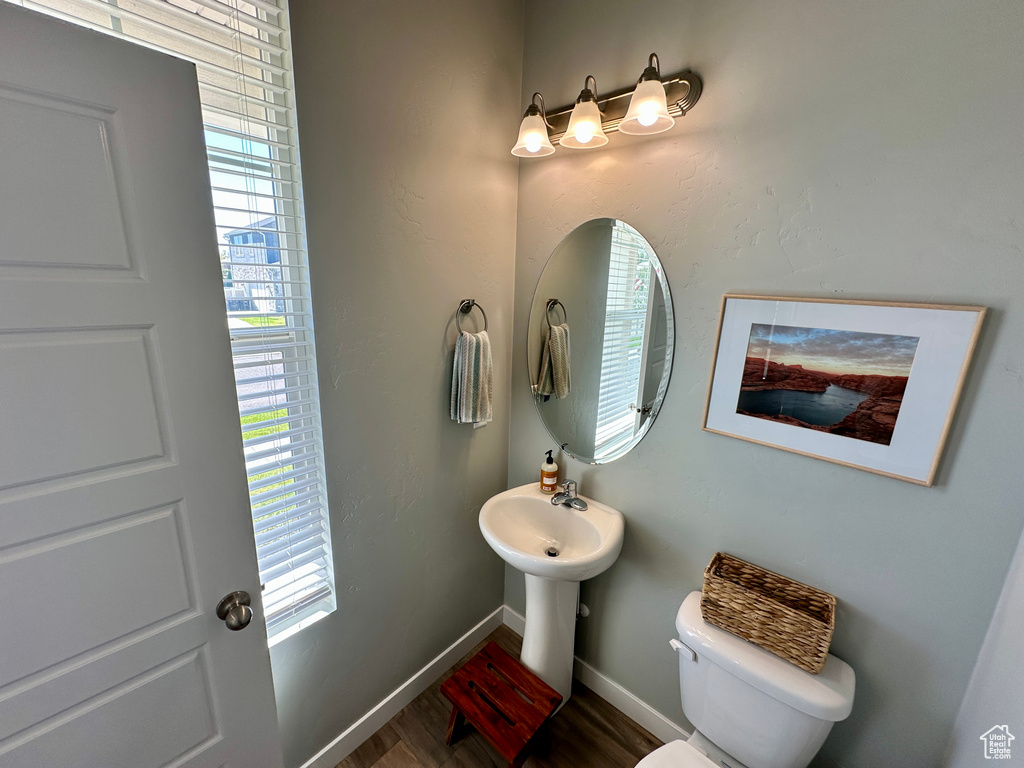 Bathroom with toilet, wood finished floors, and baseboards