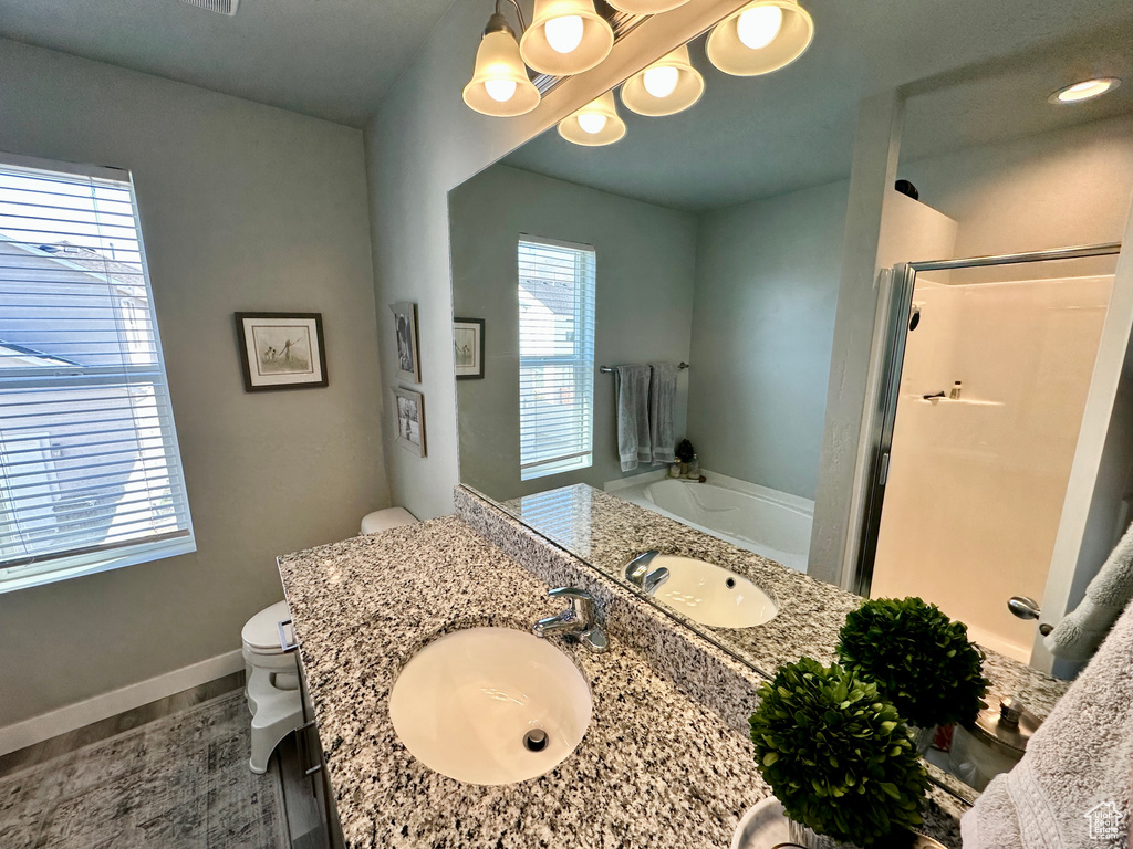 Full bath with a shower stall, a chandelier, toilet, a garden tub, and vanity