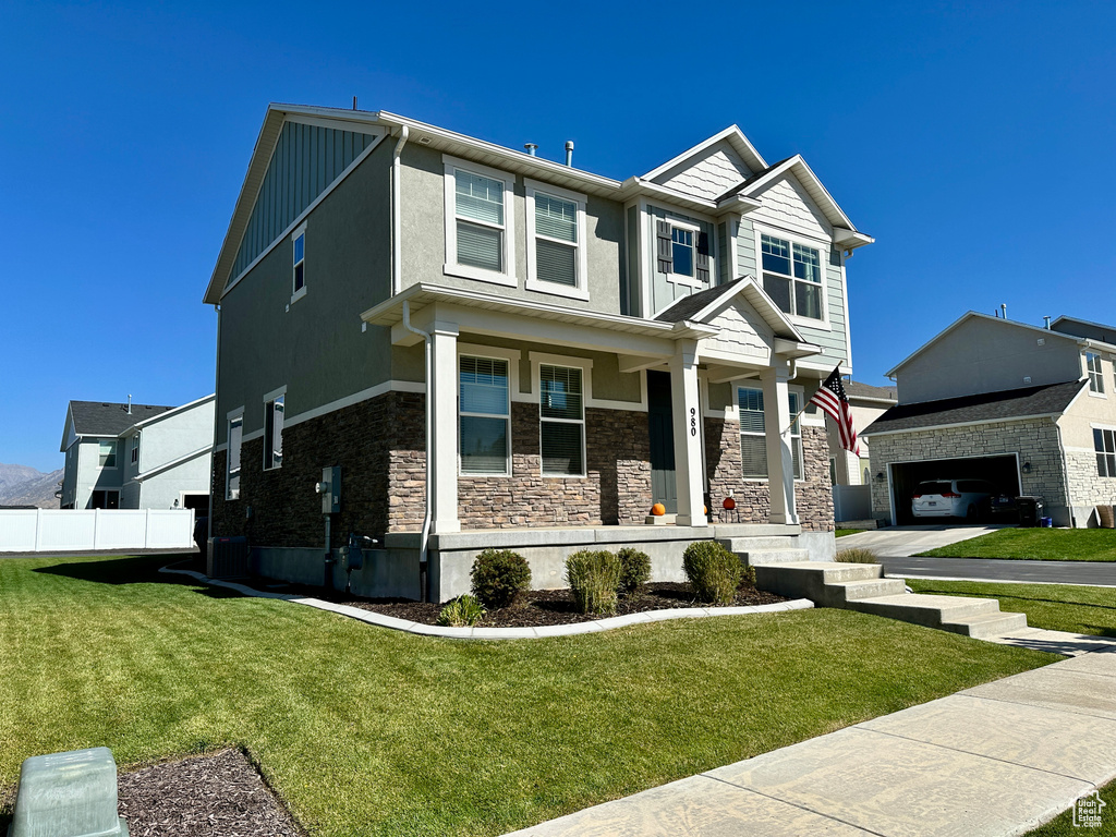 Craftsman-style home with fence, a front yard, a porch, and stone siding