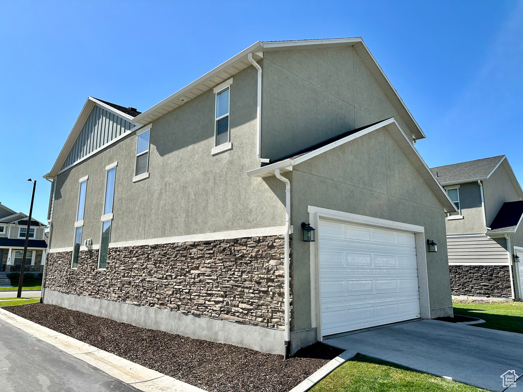 View of property exterior featuring driveway, board and batten siding, stucco siding, and stone siding