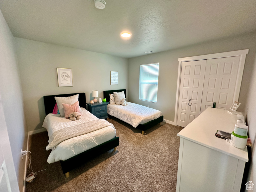 Bedroom featuring dark colored carpet, visible vents, baseboards, and a closet