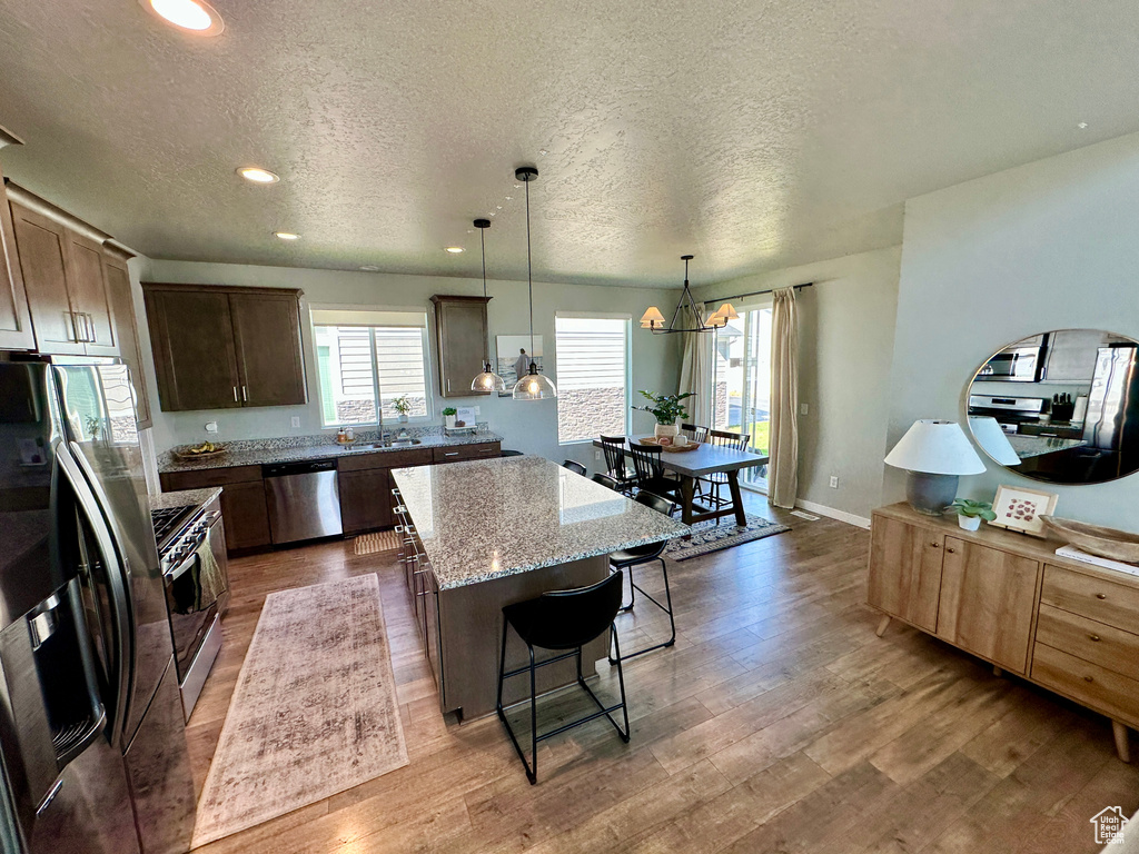 Kitchen with a center island, wood finished floors, a textured ceiling, and appliances with stainless steel finishes