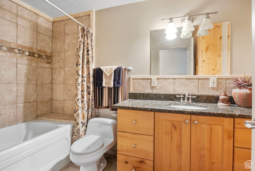 Bathroom featuring decorative backsplash, shower / bath combo, vanity, and toilet