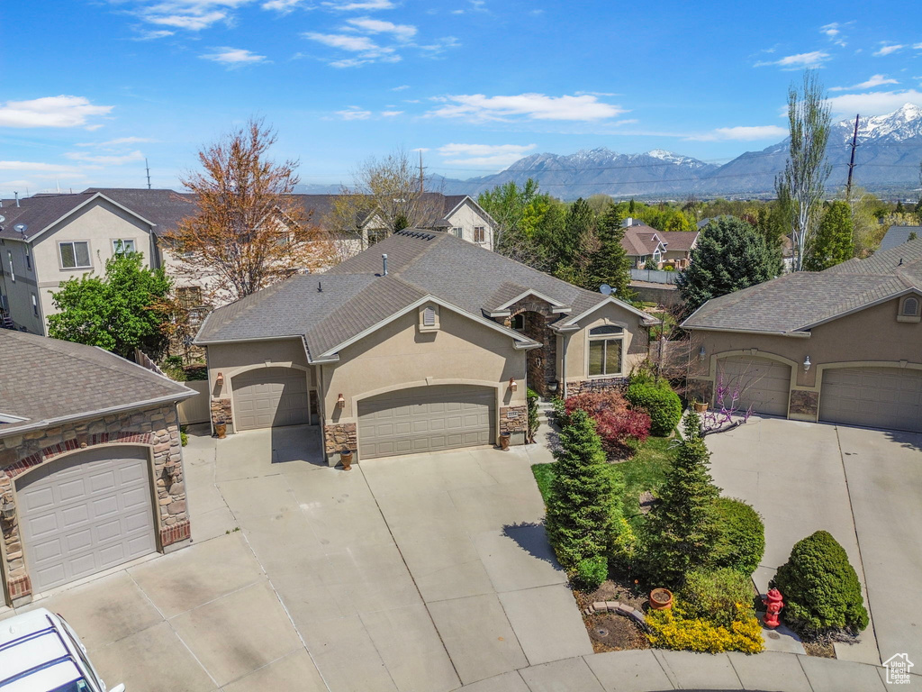 View of front of house with a residential view, a mountain view, driveway, stone siding, and a garage