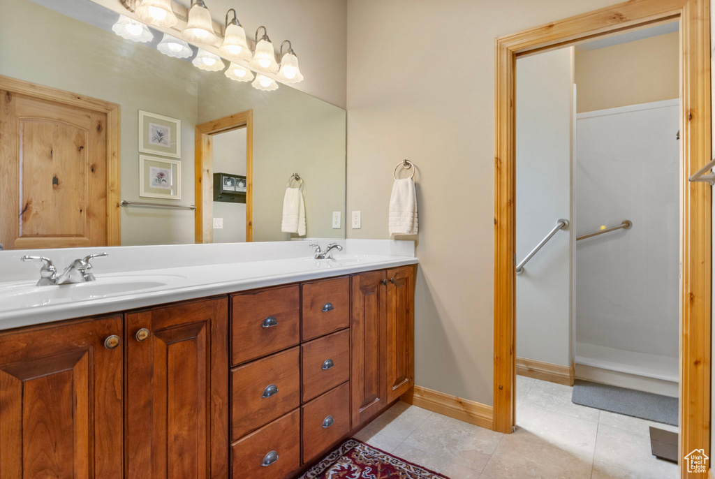Full bath featuring baseboards, tile patterned floors, a sink, and double vanity