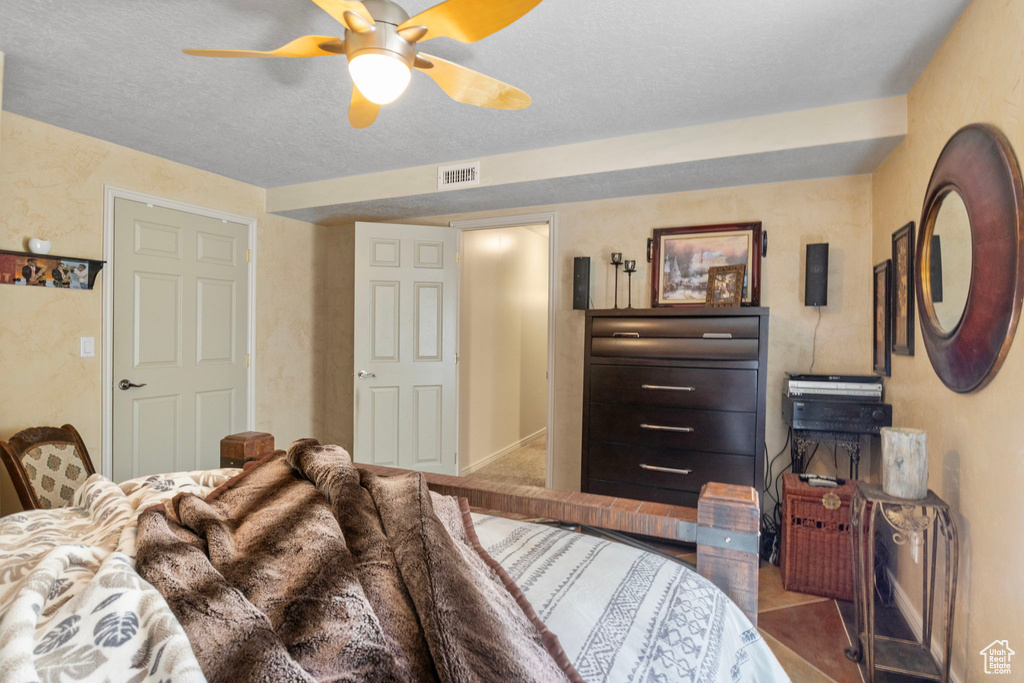 Bedroom with ceiling fan, a textured ceiling, and visible vents
