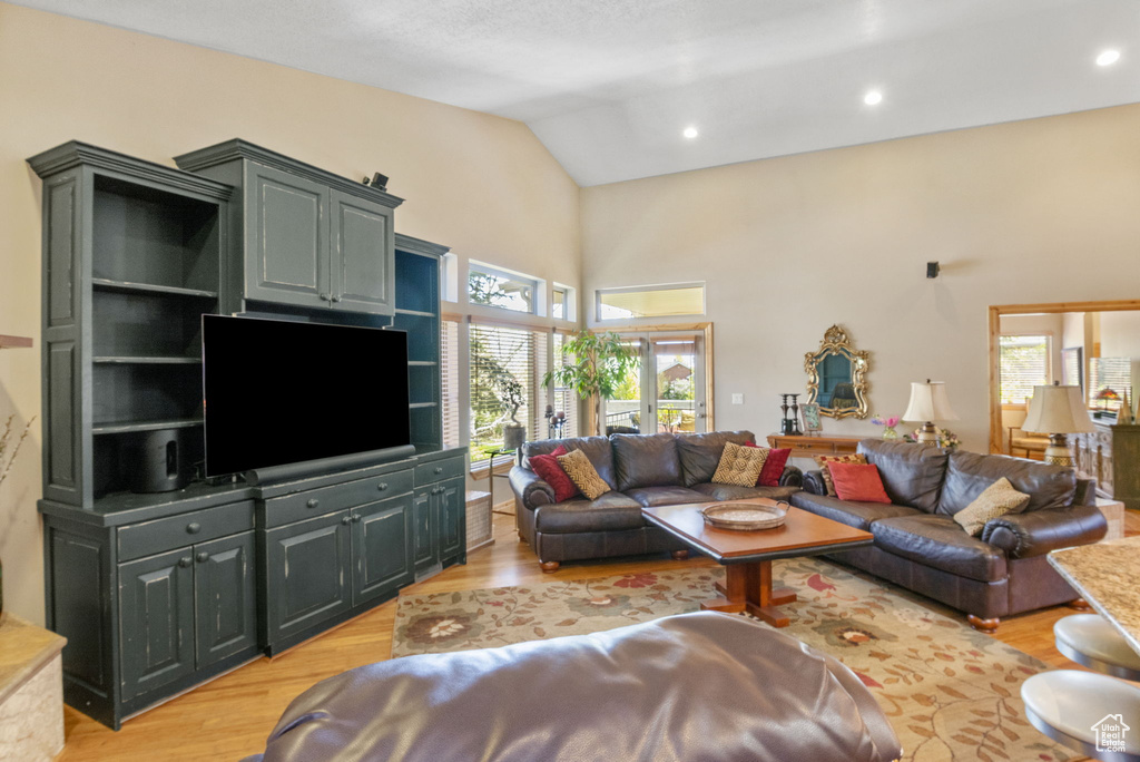 Living area with recessed lighting, light wood-style floors, and high vaulted ceiling