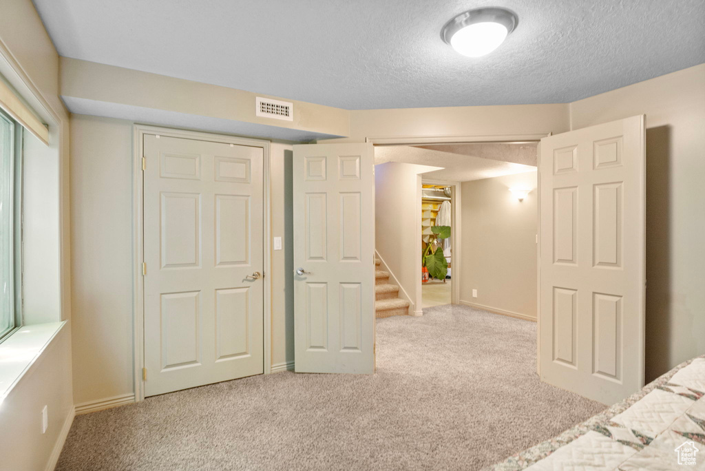 Unfurnished bedroom with baseboards, visible vents, carpet floors, and a textured ceiling
