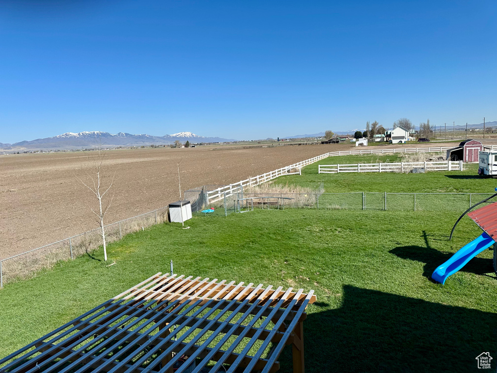View of yard featuring a mountain view, a rural view, and fence