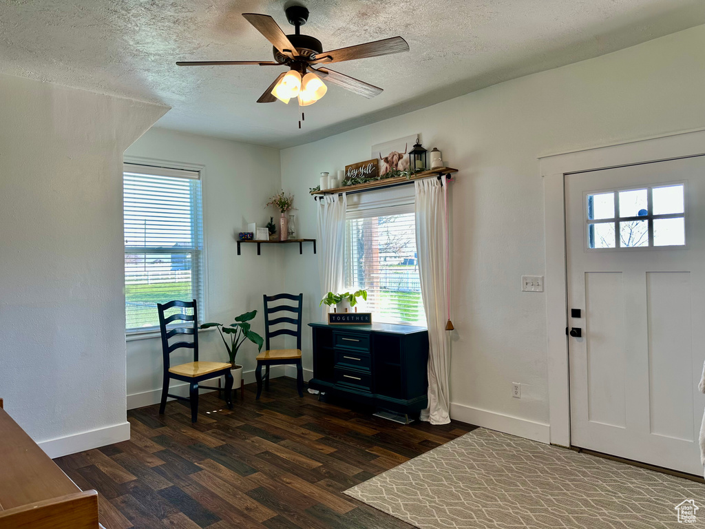 Living area featuring a textured ceiling, dark wood-style flooring, and baseboards