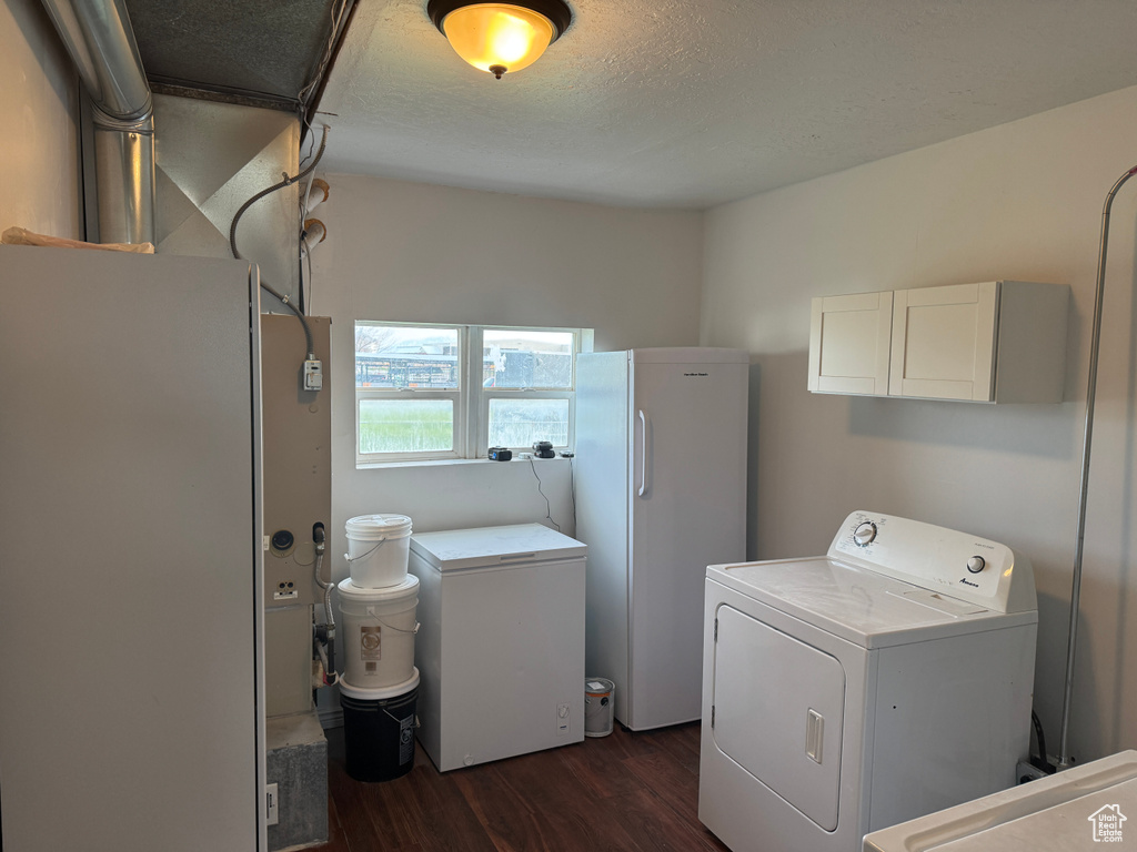 Laundry room with dark wood-style flooring, cabinet space, and a textured ceiling