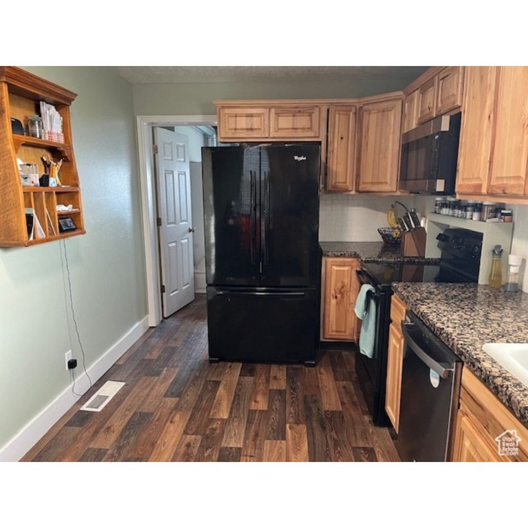 Kitchen with baseboards, visible vents, black appliances, and dark wood-type flooring