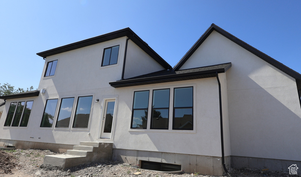Rear view of property with entry steps and stucco siding