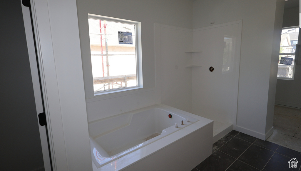 Bathroom with a bath, healthy amount of natural light, and tile patterned flooring