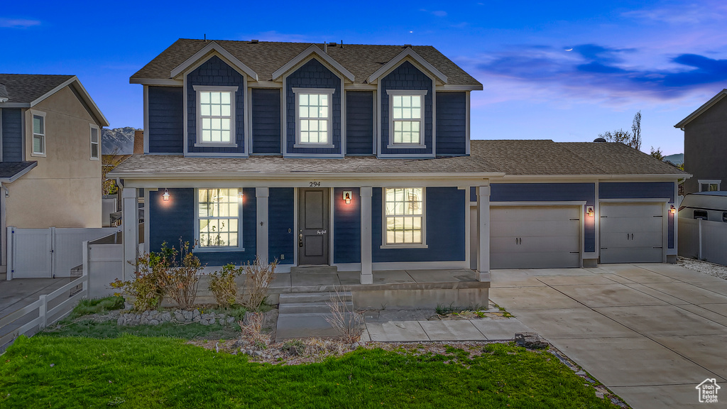 Traditional-style home featuring concrete driveway, a garage, a shingled roof, and fence