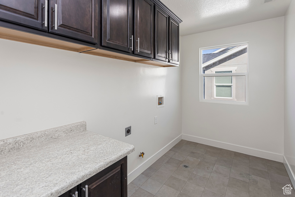 Clothes washing area with hookup for an electric dryer, washer hookup, cabinet space, and baseboards