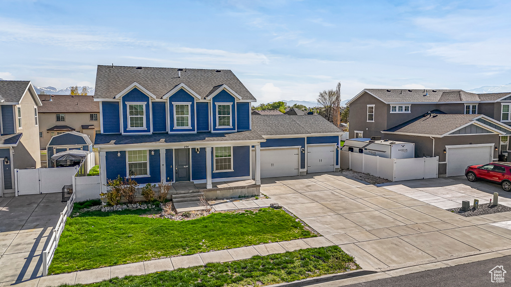 Traditional-style home featuring a front yard, a garage, a residential view, a gate, and driveway