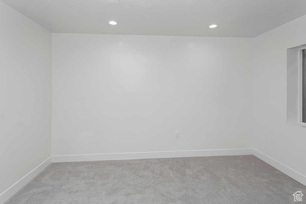 Spare room with baseboards, recessed lighting, and light colored carpet