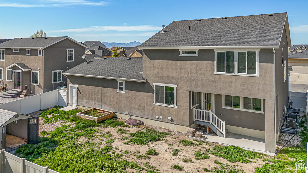 Rear view of property featuring a garden, a fenced backyard, and roof with shingles