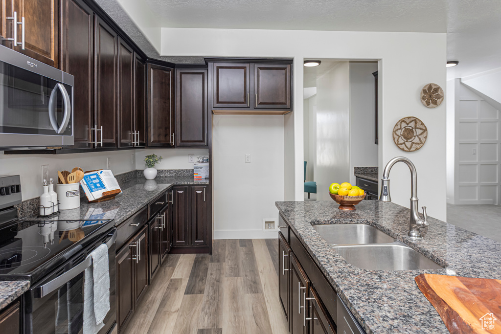 Kitchen featuring electric range, stainless steel microwave, dark stone counters, and a sink