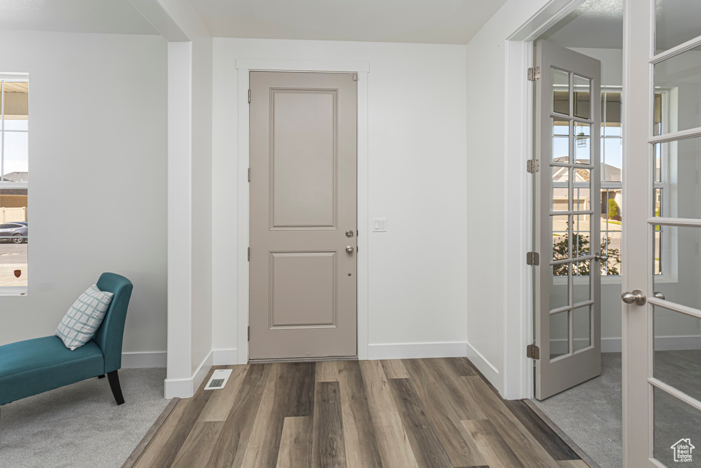 Foyer entrance with baseboards, visible vents, wood finished floors, and french doors