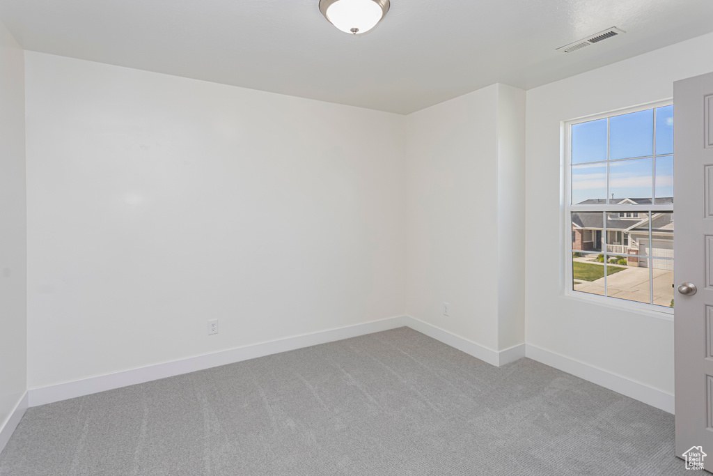 Empty room with baseboards, visible vents, and carpet