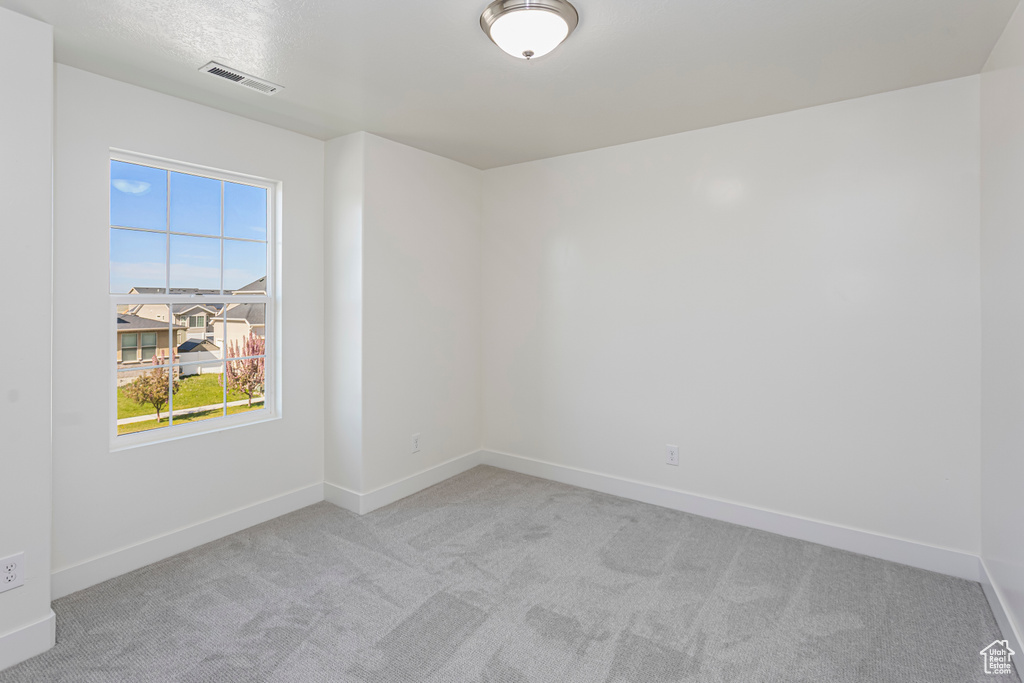 Carpeted spare room featuring baseboards and visible vents