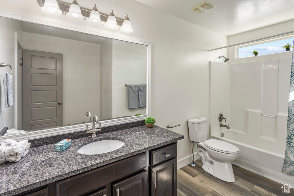 Full bath with vanity, shower / bath combination with curtain, toilet, visible vents, and wood finished floors