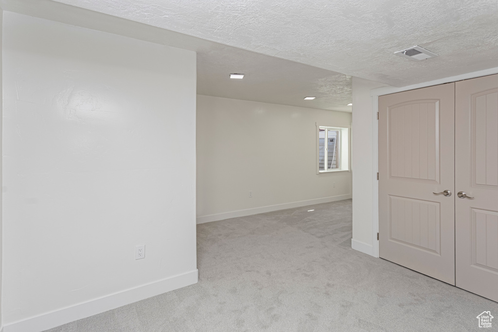 Spare room featuring a textured ceiling, visible vents, baseboards, and light carpet