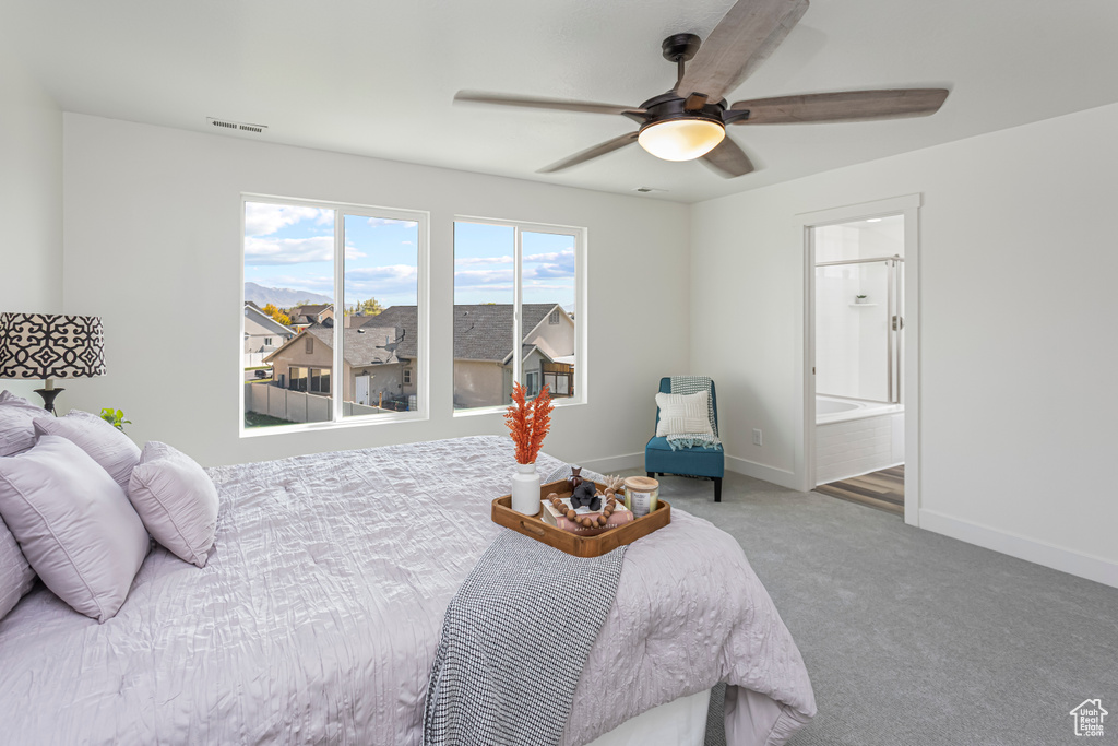 Carpeted bedroom with baseboards, visible vents, ceiling fan, and connected bathroom