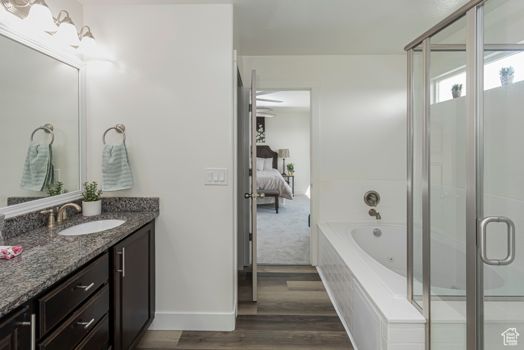 Ensuite bathroom featuring vanity, a whirlpool tub, a stall shower, baseboards, and wood finished floors