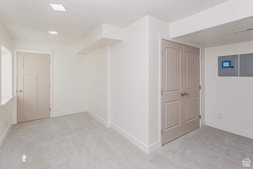 Interior space featuring a textured ceiling, electric panel, visible vents, and baseboards