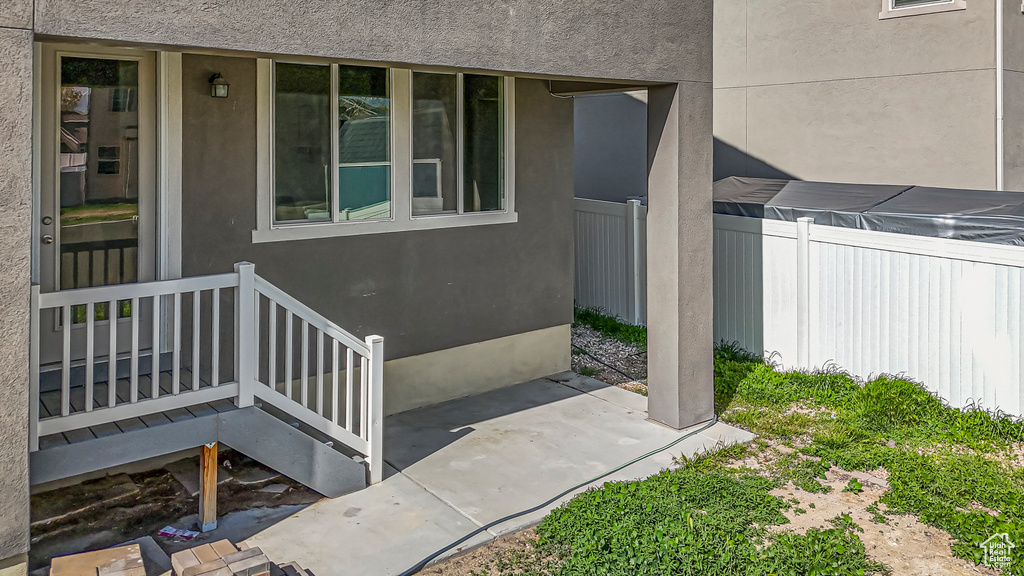 Doorway to property with a patio area, stucco siding, and fence
