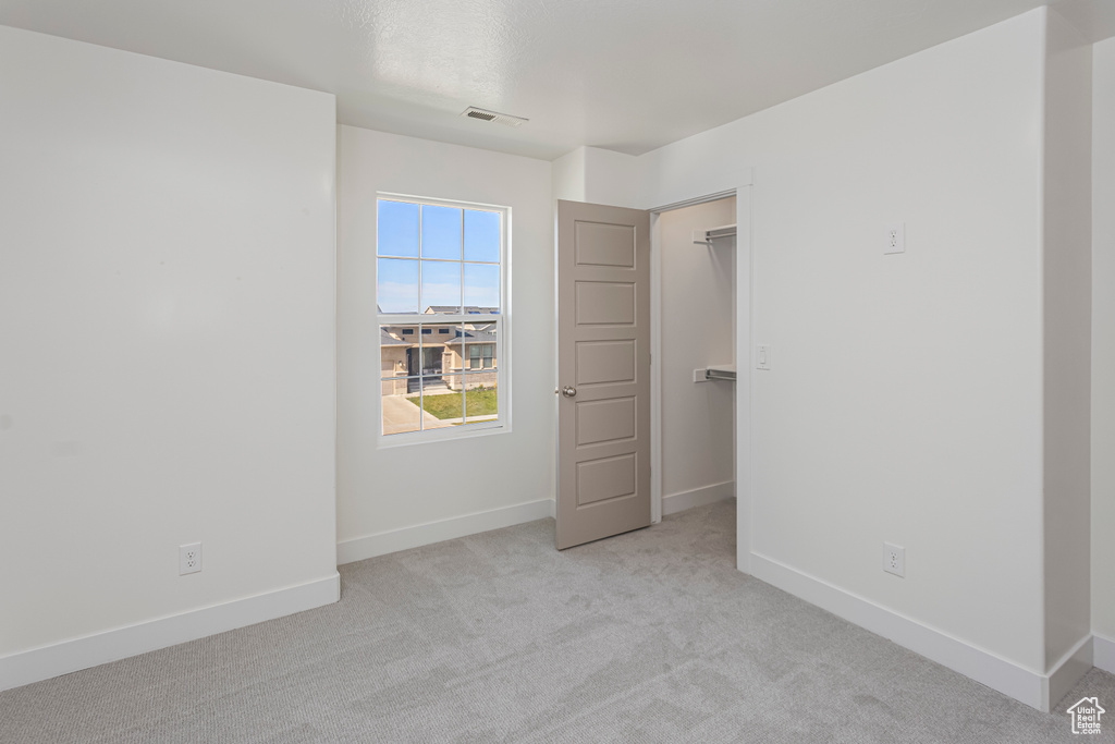 Unfurnished bedroom featuring baseboards, visible vents, carpet floors, and a walk in closet