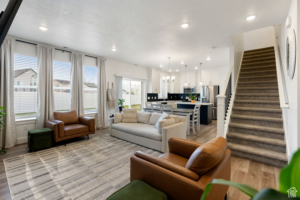 Living room with light wood-type flooring, recessed lighting, a chandelier, and stairway