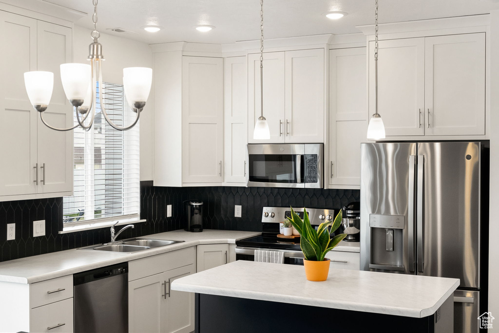 Kitchen with light countertops, white cabinets, stainless steel appliances, and a sink