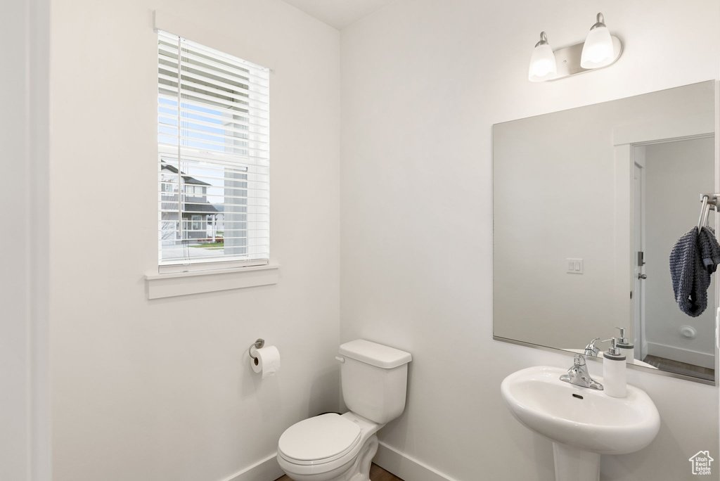Half bath featuring toilet, baseboards, and a sink