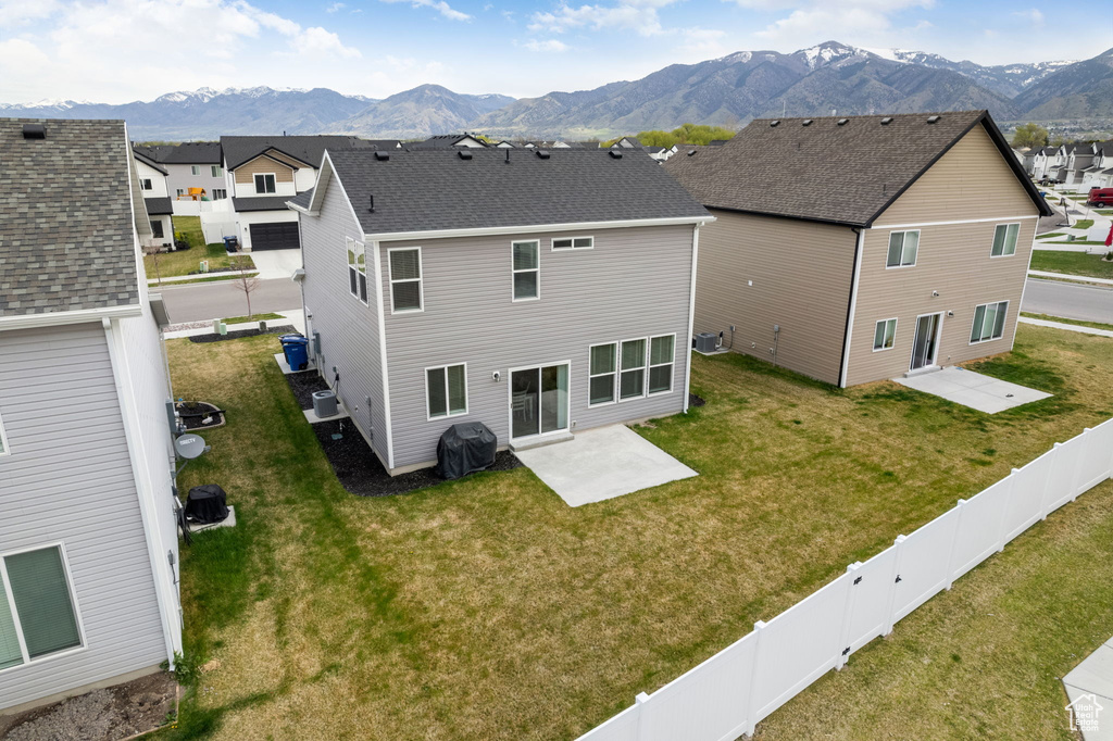 Rear view of house with a lawn, a fenced backyard, a mountain view, and a patio