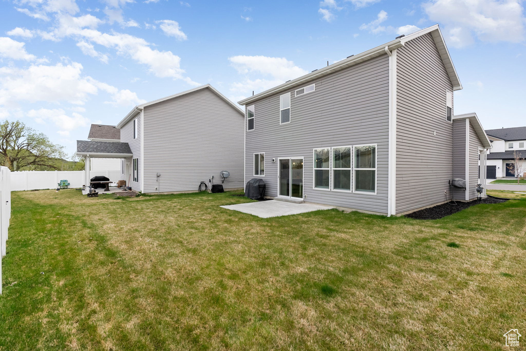 Rear view of house featuring a lawn, fence, and a patio area
