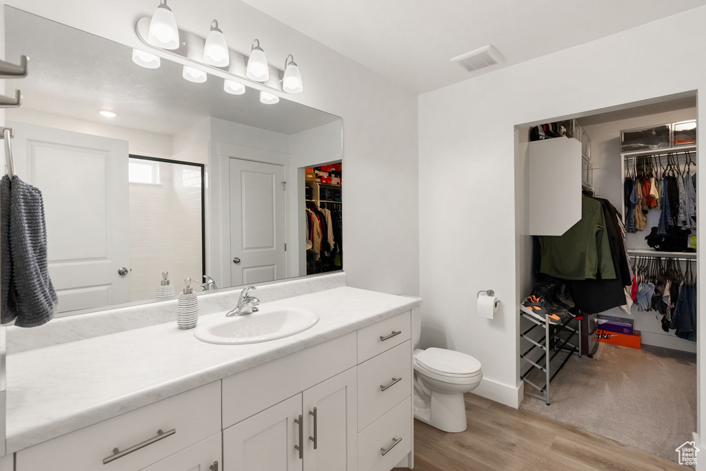 Full bathroom featuring wood finished floors, a stall shower, vanity, toilet, and visible vents