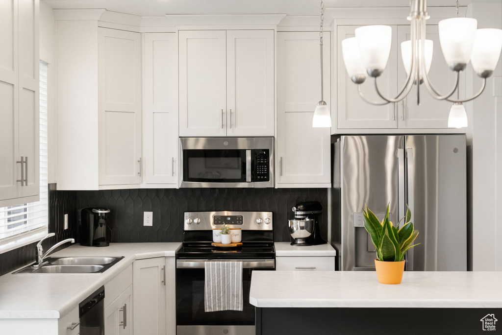 Kitchen with light countertops, white cabinetry, stainless steel appliances, and a sink