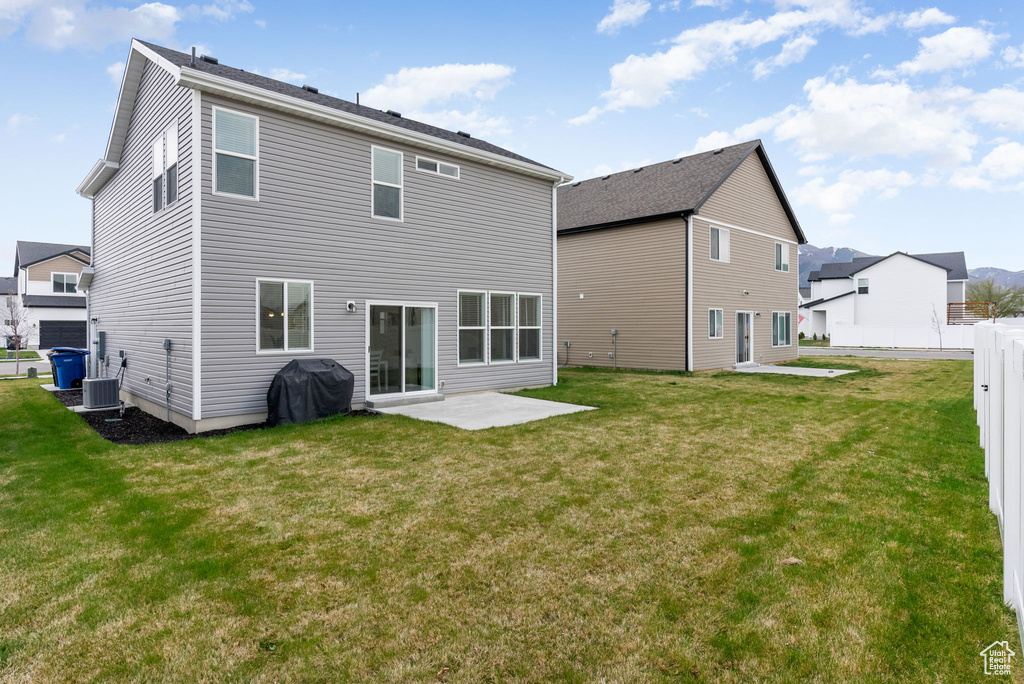 Rear view of house with fence, a patio area, a lawn, and central AC unit