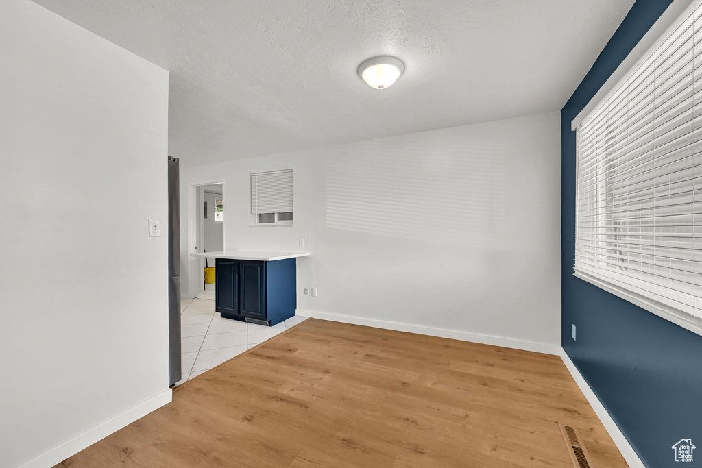 Empty room with visible vents, light wood finished floors, and baseboards