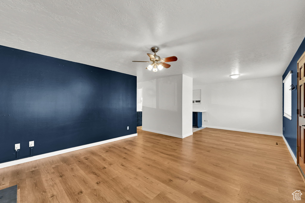 Spare room with baseboards, a textured ceiling, ceiling fan, and wood finished floors