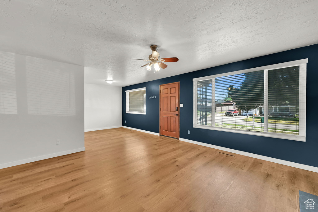 Interior space featuring baseboards, a textured ceiling, ceiling fan, and wood finished floors
